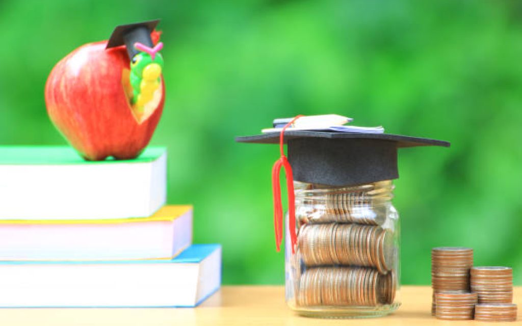 Graduation hat on the glass bottle and books on natural green background, Saving money for education concept